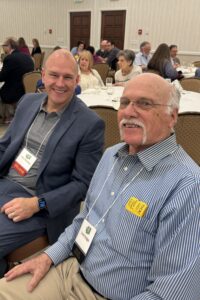 Two men sitting next to each other at a conference.